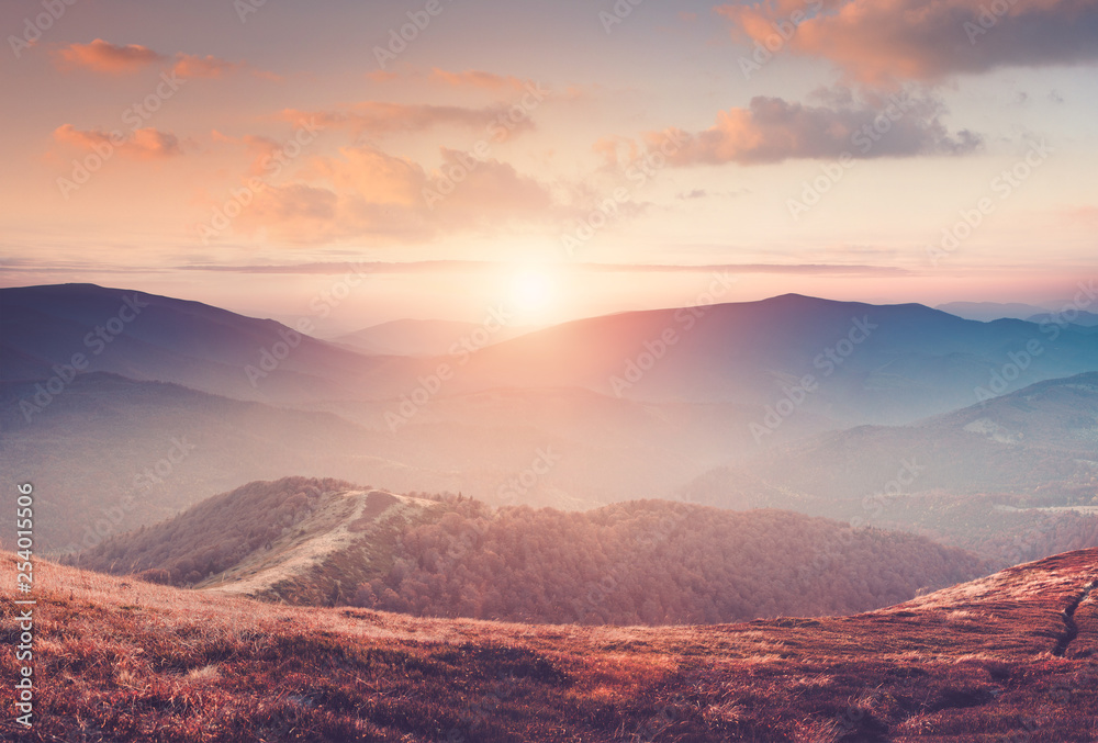 Beautiful landscape in the mountains at sunset with haze and cloudy sky. View of magnificent natural scenery of mountains hills. Filtered image:cross processed retro effect.