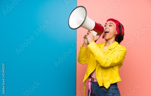 Young woman with yellow jacket shouting through a megaphone