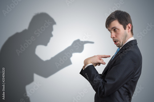 Shadow of man is pointing and blaming businessman. Conscience concept. photo