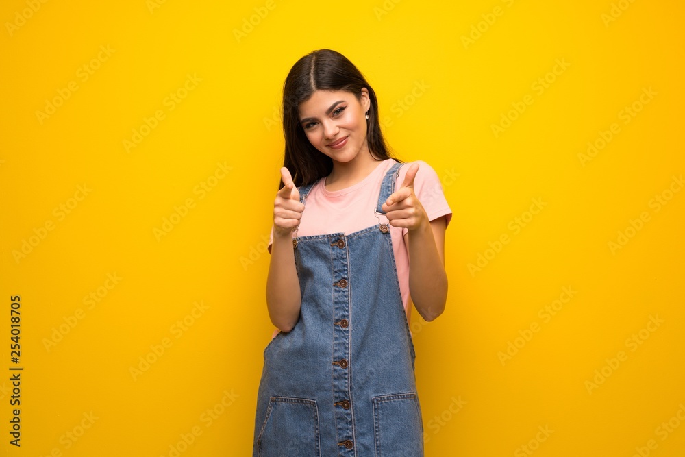 Teenager girl over yellow wall pointing to the front and smiling Teenager girl over yellow wall pointing to the front and smiling