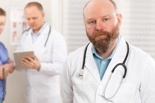 Portrait of a confident real doctor standing in front of his health team