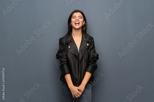 Teenager girl over grey wall shouting to the front with mouth wide open