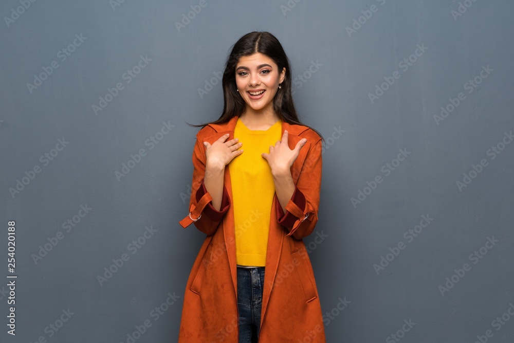 Teenager girl with coat over grey wall with surprise facial expression Teenager girl with coat over grey wall with surprise facial expression