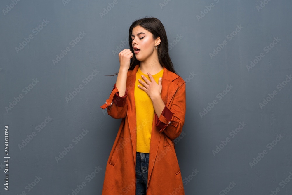 Teenager girl with coat over grey wall is suffering with cough and feeling bad Teenager girl with coat over grey wall is suffering with cough and feeling bad