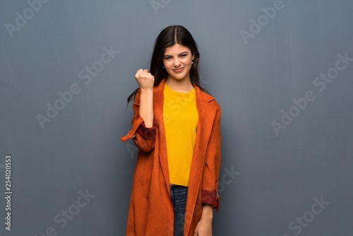 Teenager girl with coat over grey wall with angry gesture © luismolinero