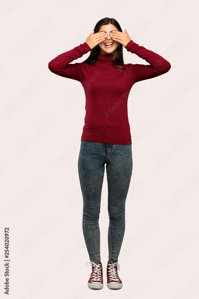 A full-length shot of a Teenager girl with turtleneck covering eyes by hands. Surprised to see what is ahead over isolated background A full-length shot of a Teenager girl with turtleneck covering eyes by hands. Surprised to see what is ahead over isolated background