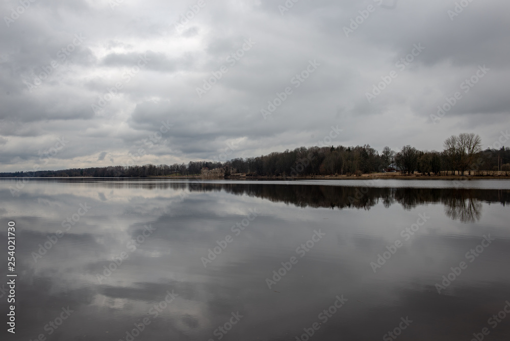 riverside landscape in latvia with dark water and dirty shore line riverside landscape in latvia with dark water and dirty shore line