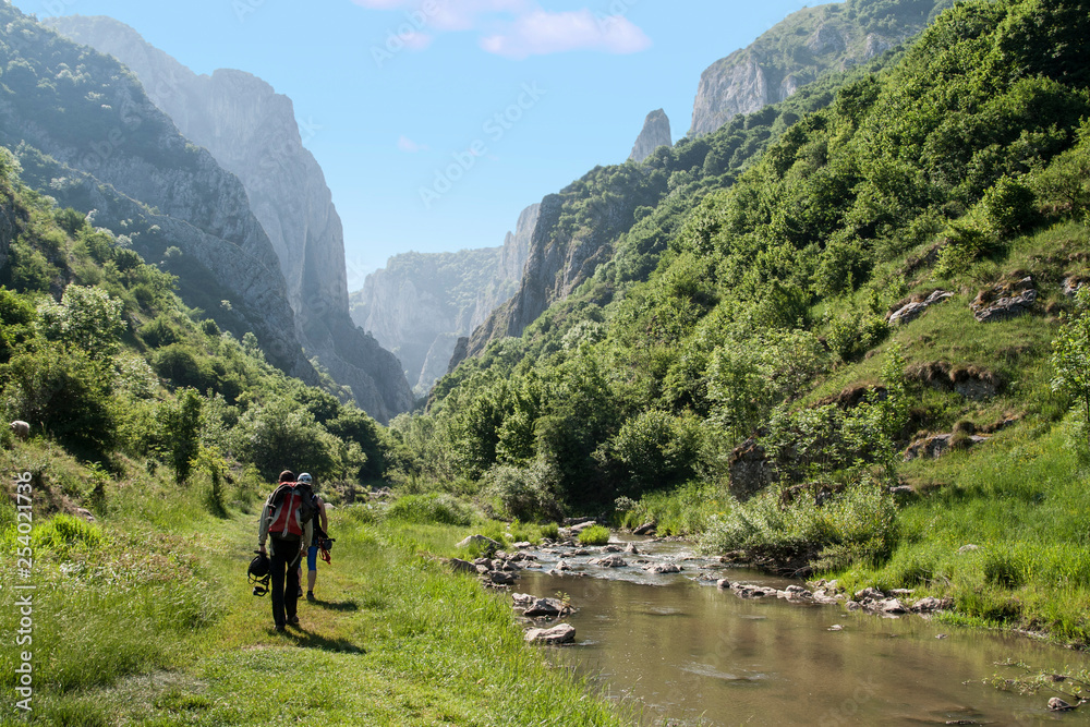 Climbers walking through a valley next to a river