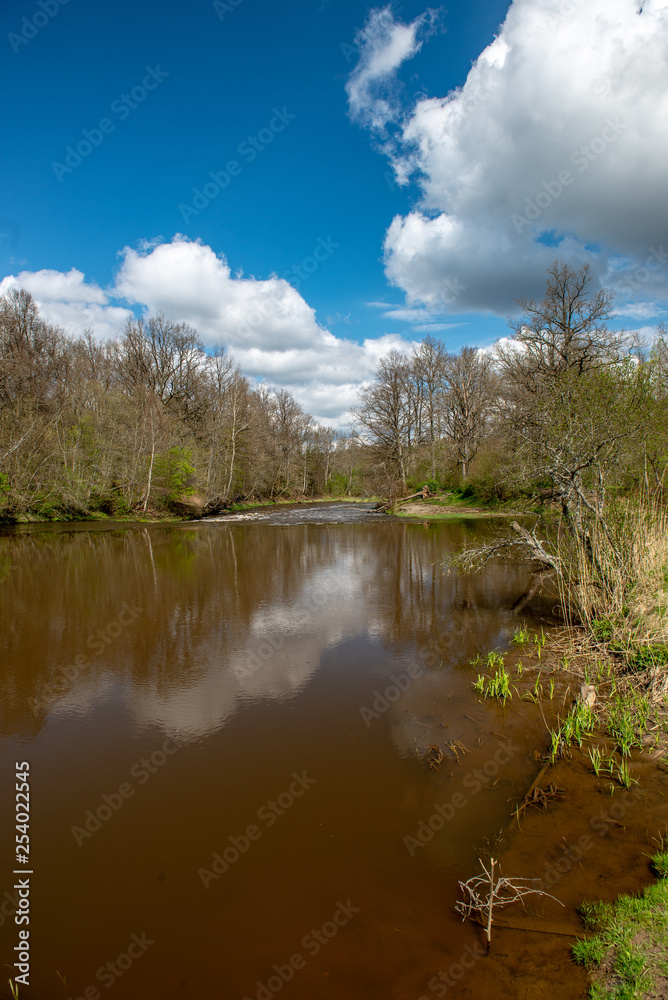 riverside landscape in latvia with dark water and dirty shore line riverside landscape in latvia with dark water and dirty shore line