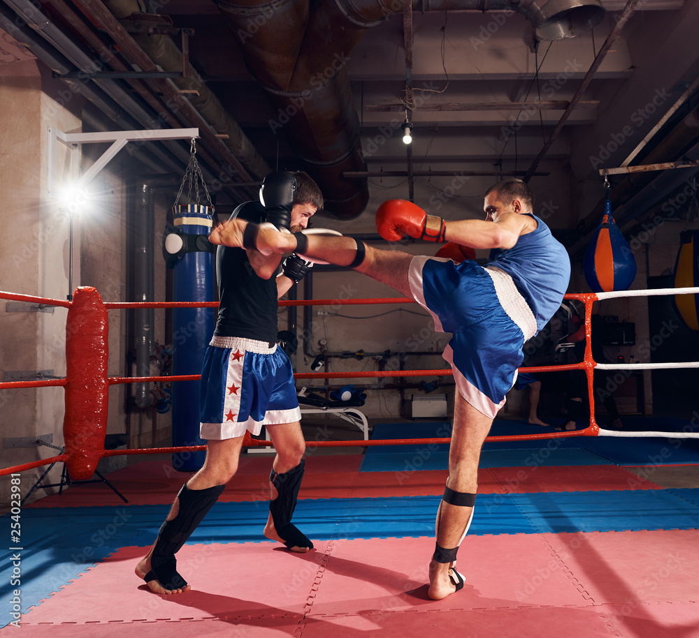 Φωτογραφία Two active men fighters exercising kickboxing in the ring at the health club