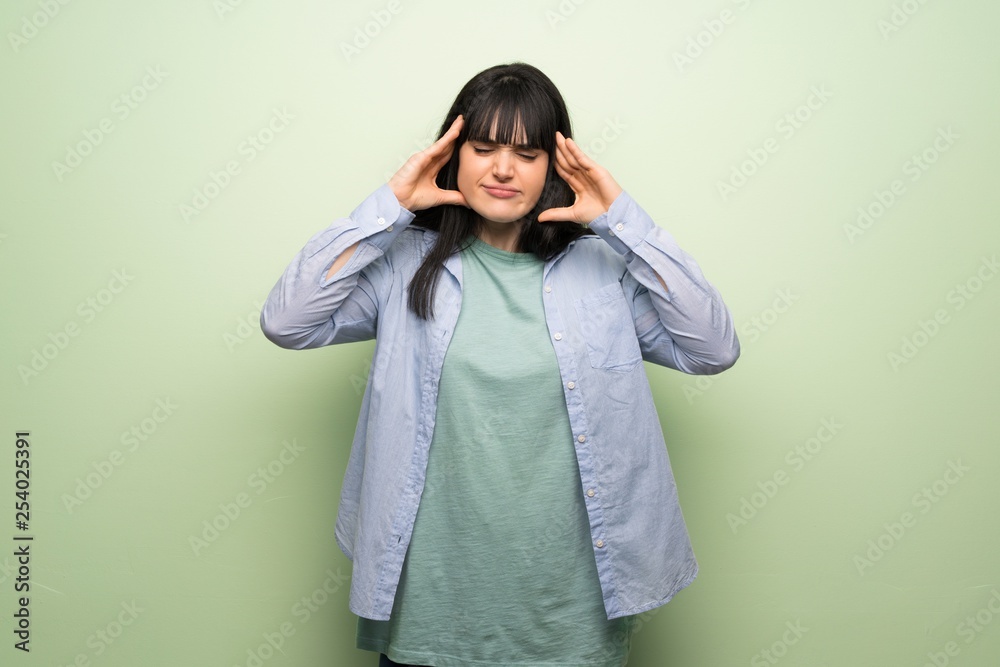 Young woman over green wall unhappy and frustrated with something