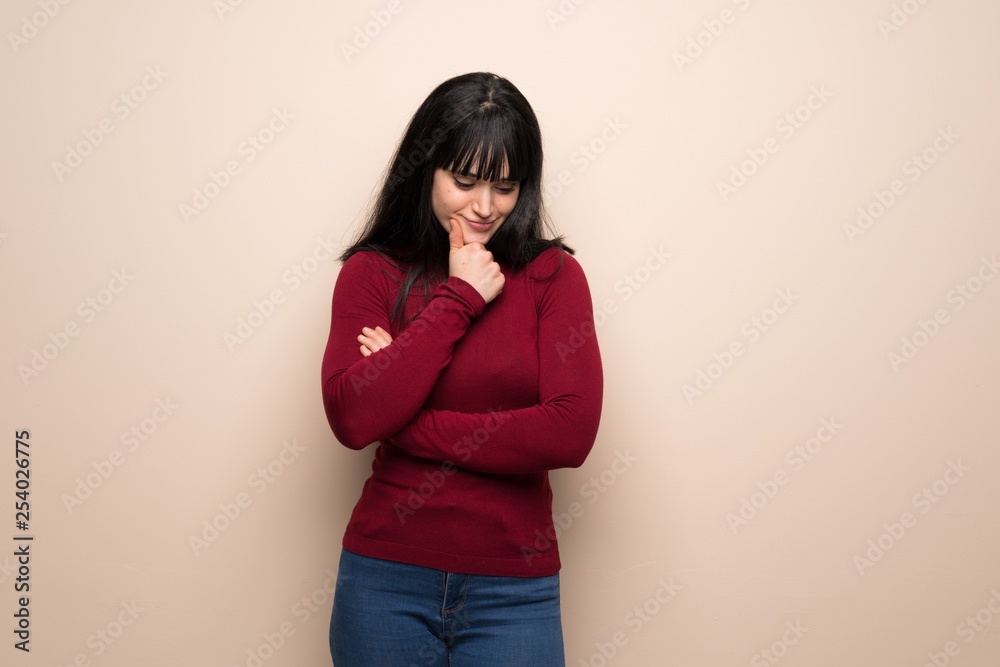 Young woman with red turtleneck looking down with the hand on the chin Young woman with red turtleneck looking down with the hand on the chin