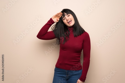 Young woman with red turtleneck saluting with hand