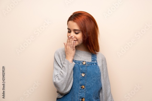 Young redhead woman over isolated background posing with arms at hip and laughing