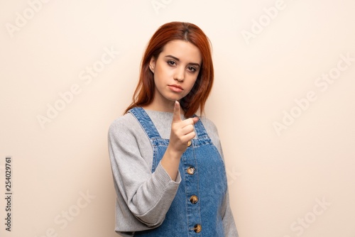 Young redhead woman over isolated background serious and pointing to the front
