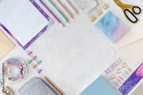 View from above of flatlay of stationery on white table background. Office or school stationery on pastel female desk