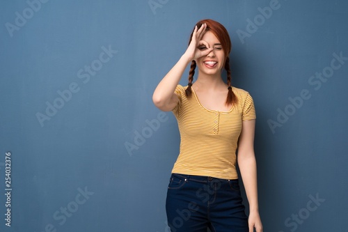 Young redhead woman over blue background makes funny and crazy face emotion © luismolinero
