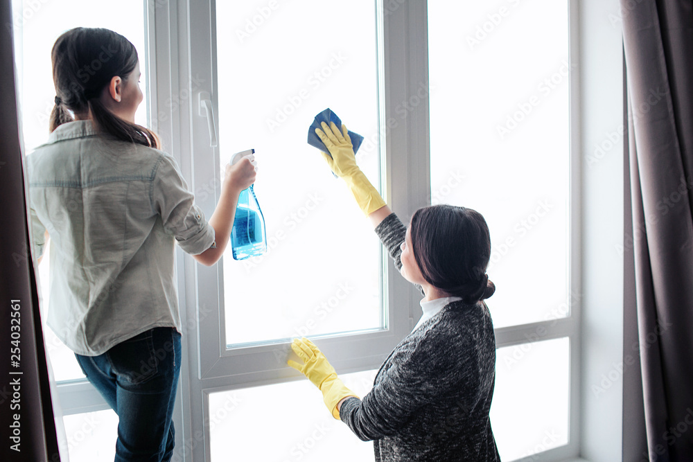 Beautiful brunette caucasian mother and daughter cleaning window ...