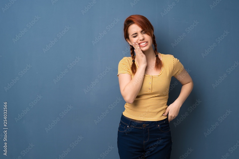 Young redhead woman over blue background with toothache Young redhead woman over blue background with toothache