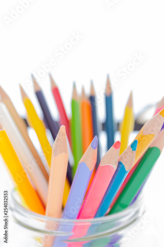 Colorful pencils in glass holder on a white background