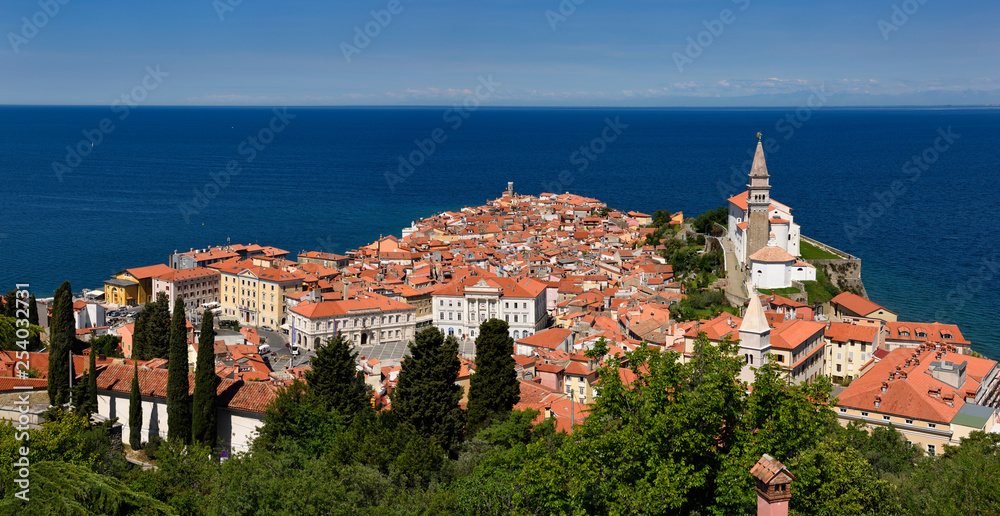 Panorama of Cape Madonna at Point of Piran Slovenia on blue Adriatic Sea with Tartini Square courthouse City Hall and St George's Catholic church