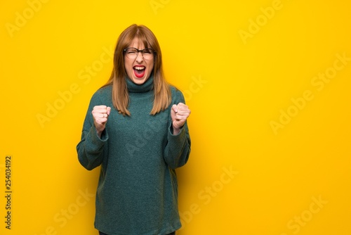 Woman with glasses over yellow wall frustrated by a bad situation
