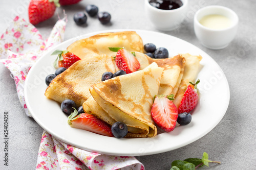 Thin pancakes with strawberries and blueberries, jam, condensed milk, delicious Breakfast. Russian traditional dessert for Shrovetide celebration (maslenitsa). French crepes