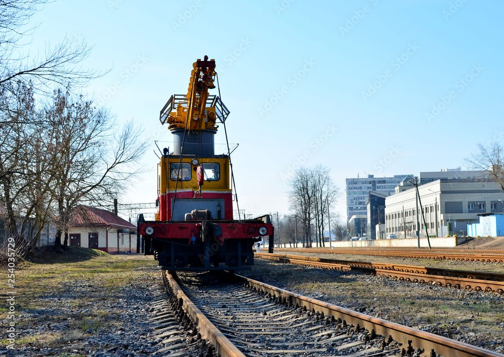 Railway crane on the platform, moving along the railway track. Special construction train for maintenance of railway, rail, sleepers