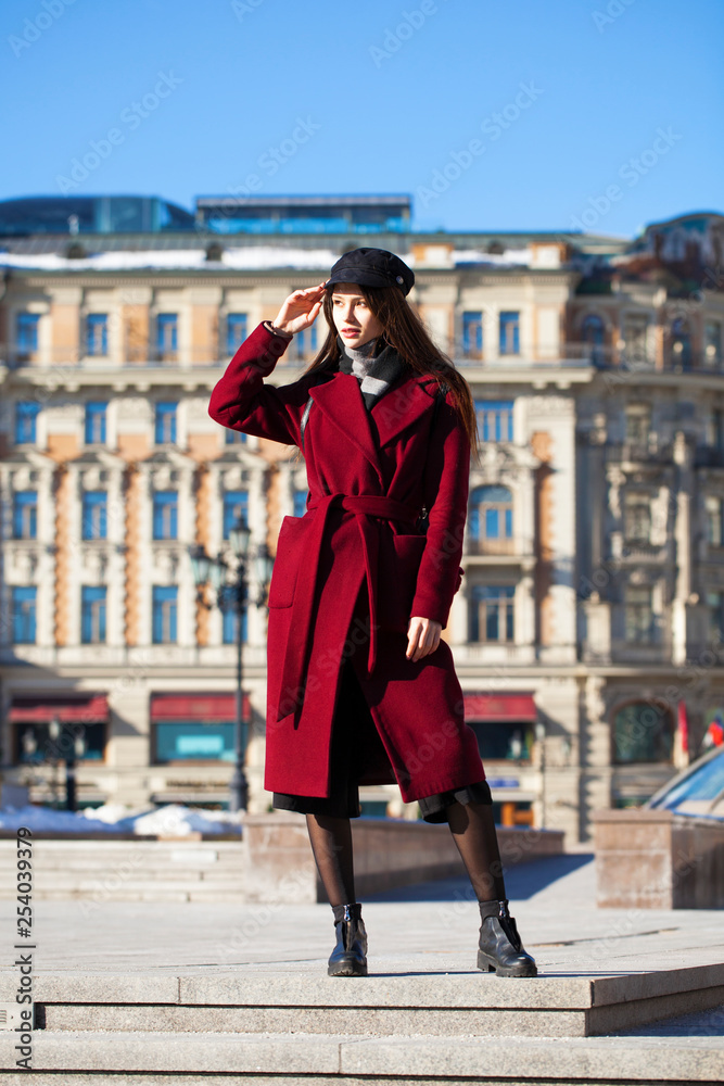 Beautiful girl in stylish in a long burgundy coat