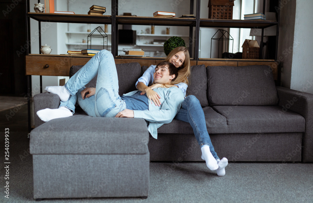 Fototapeta premium Sweet young couple in blue denim cloth playing on the sofa together