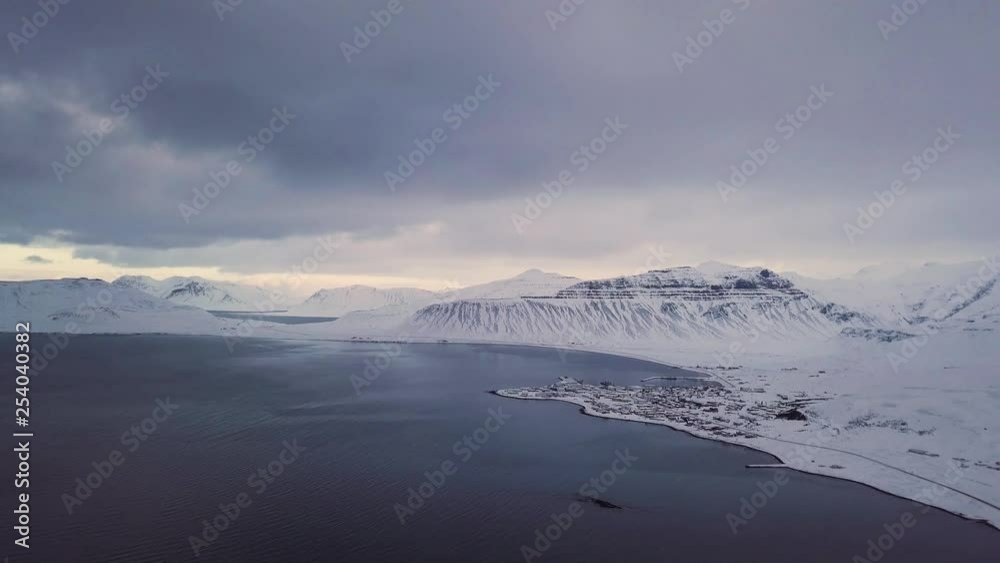 Aerial backwards dolly, small icelandic village next to the sea, during winter.