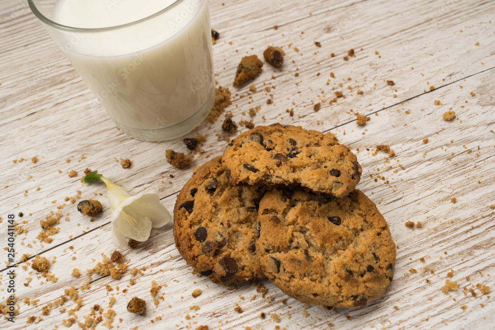 Top view of chocolate chip cookies, crumbs and a glass of milk on a wooden table Top view of chocolate chip cookies, crumbs and a glass of milk on a wooden table