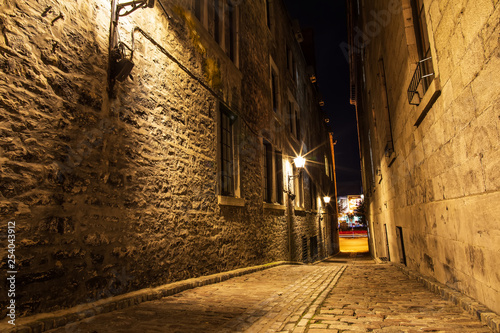 Small street and historical buildings in the historic site of Old Port from Montreal, night view. Scenic background of Canadian history. Old urban architecture of Montreal culture patrimony.