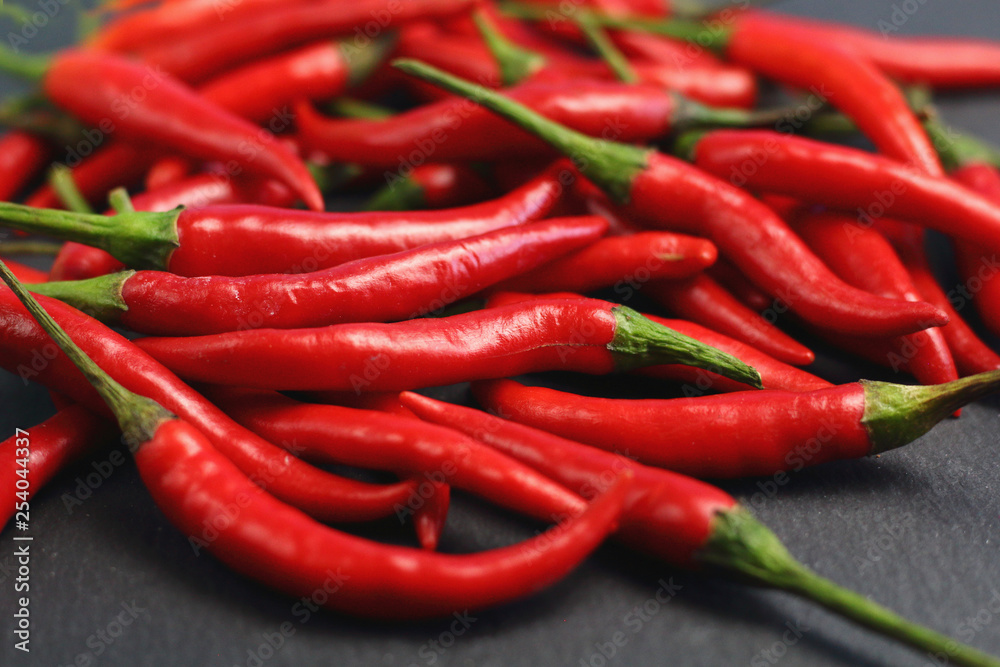 A lot of sharp hot spice red chilli cayenne pepper with wet drops of freshness water dew on a black graphite slate stone surface. Natural vegeterian diet organic vegetable. Dark food foto