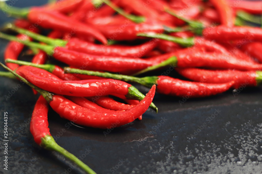 A lot of sharp hot spice red chilli cayenne pepper with wet drops of freshness water dew on a black graphite slate stone surface. Natural vegeterian diet organic vegetable. Dark food foto