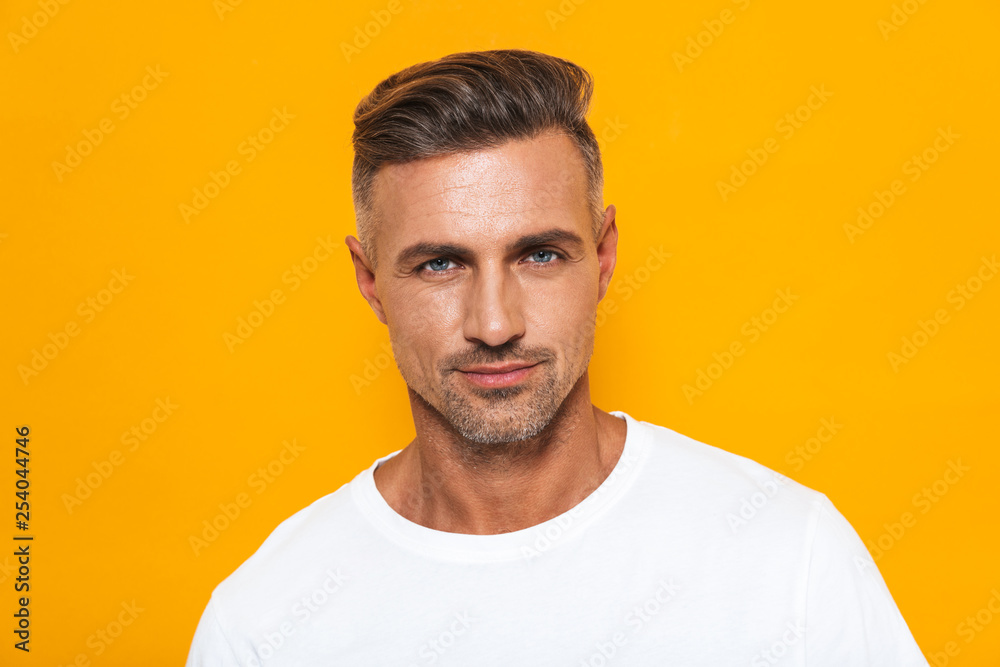Fototapeta premium Image of sexual man 30s in white t-shirt posing at camera with confident look