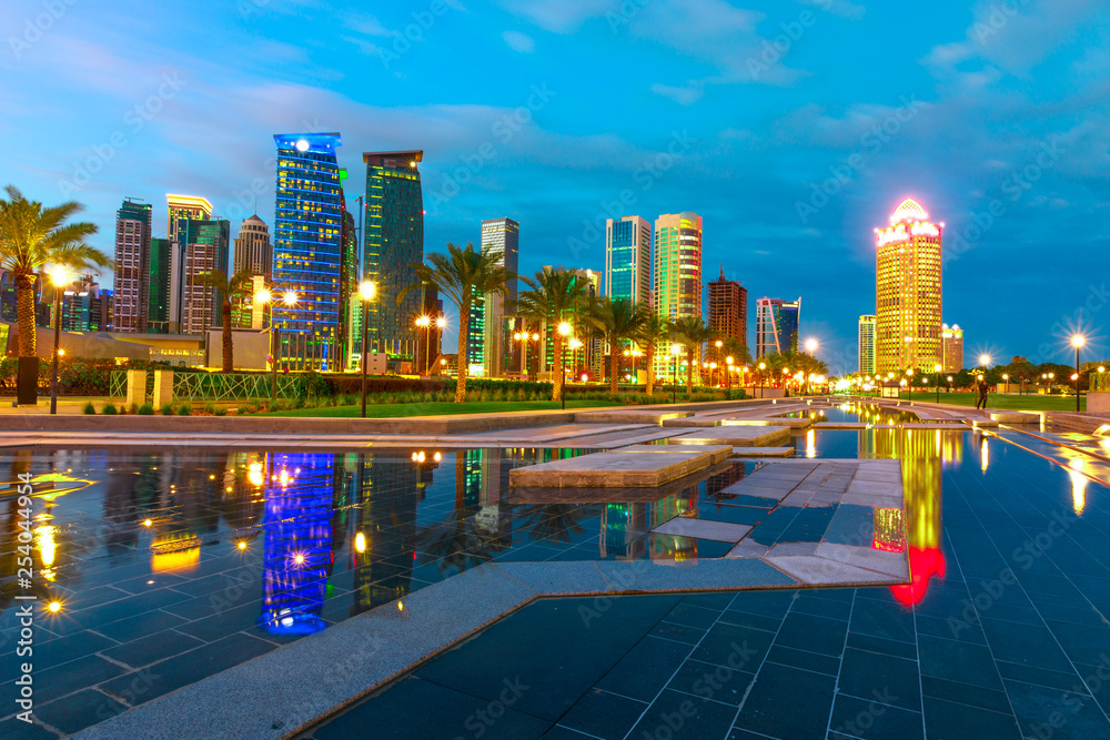 Obraz premium Doha West Bay high rises at blue hour reflecting in the water of park in Downtown. Modern skyscrapers of Doha skyline in Qatar, Middle East, Arabian Peninsula in Persian Gulf at twilight.
