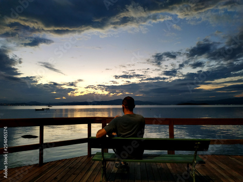 man sitting on a bench at sunset