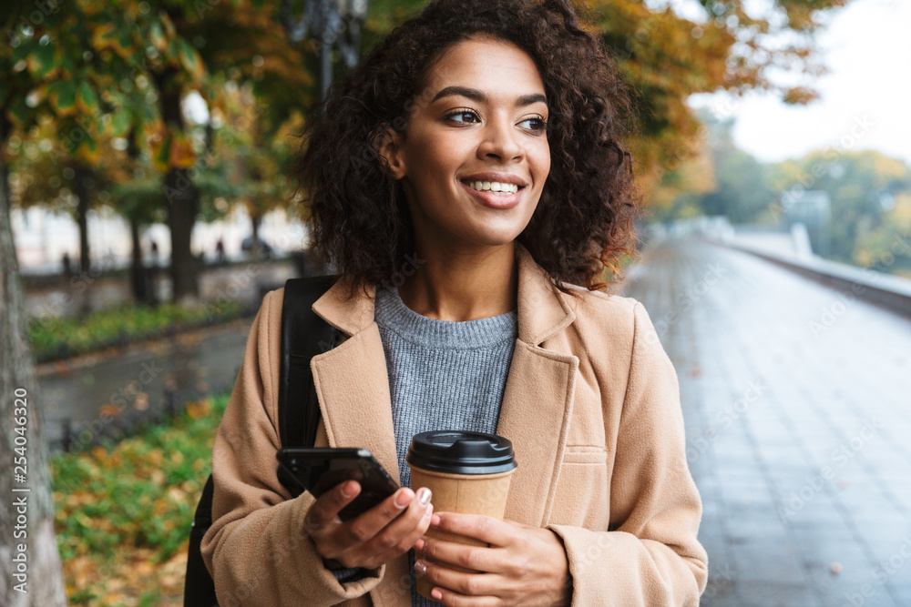 Cheerful young african woman wearing coat walking Cheerful young african woman wearing coat walking