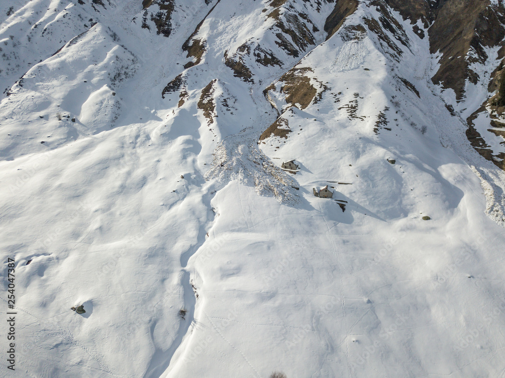 Aerial view of snow avalanche on mountain slope. Wet snow in spring sliding downhill. Aerial view of snow avalanche on mountain slope. Wet snow in spring sliding downhill.