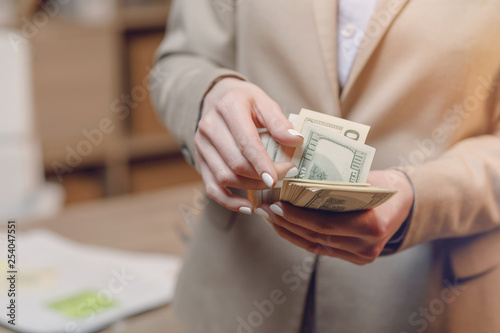 Hand giving money. Businesswoman in eyeglasses holding dollar currency.