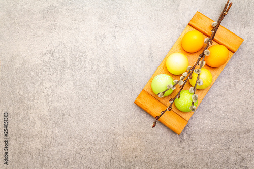 Easter eggs with willow seals branches. Concept on a wooden stand on a stone background  top view  copy space.