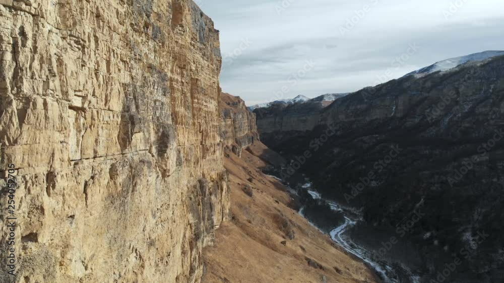 Aerial view of the movement along the rock wall of the canyon in the gorge in the Caucasus. Very close to the rock in winter when there is little snow. 4k Aerial view of the movement along the rock wall of the canyon in the gorge in the Caucasus. Very close to the rock in winter when there is little snow. 4k