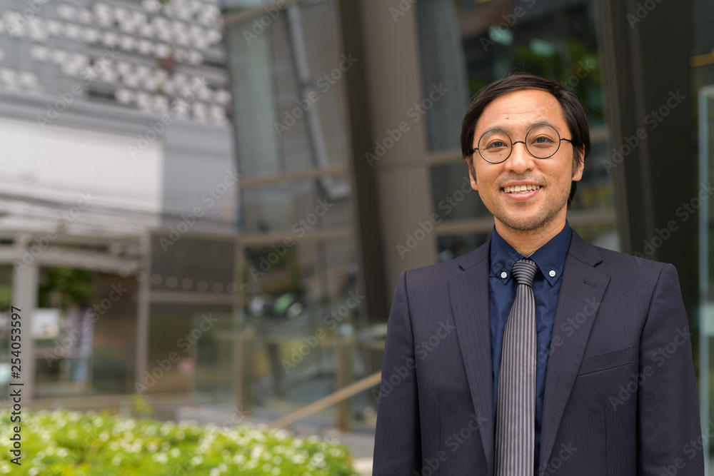 Happy Asian businessman smiling outside the office building Happy Asian businessman smiling outside the office building