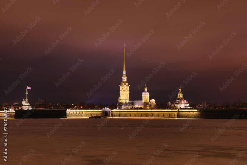 Peter and Paul Fortress of St. Petersburg, Russia in the evening or in the night and Neva river covered with the ice and snow in the cloudy weather