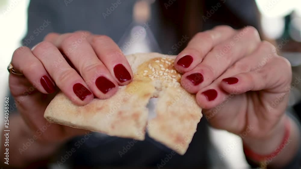 The girl holds bread in her hands, breaking it. The girl holds bread in her hands, breaking it.