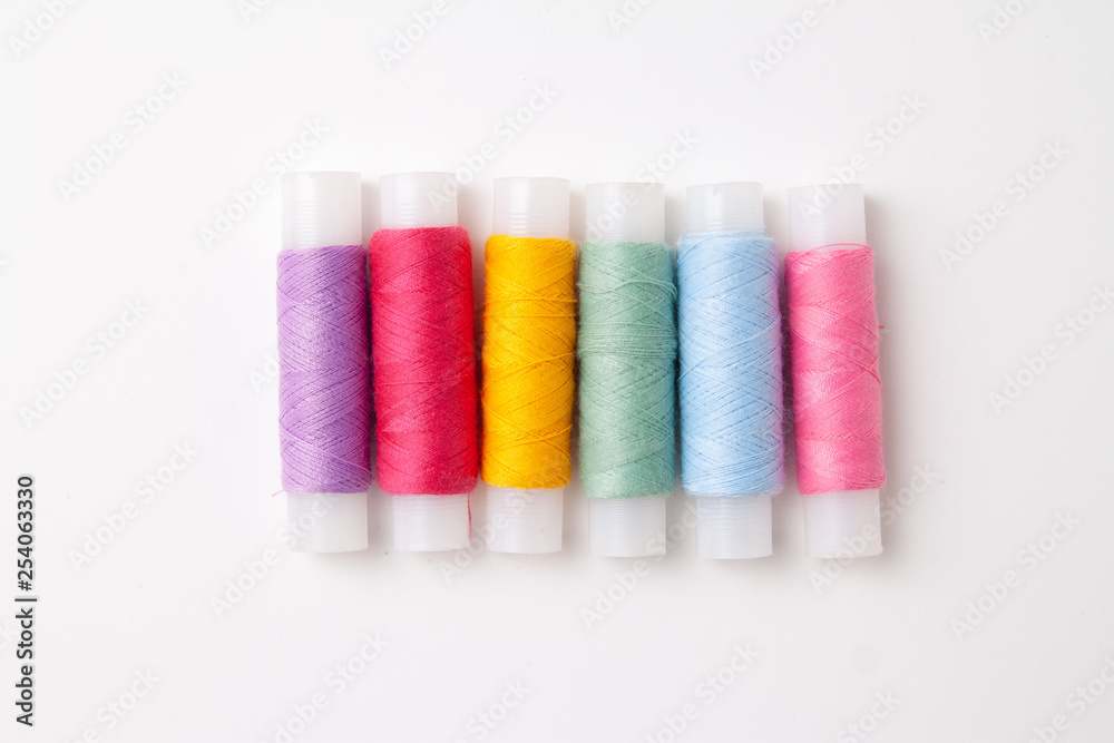 Multicolored thread coils on white background. Sewing supplies and accessories for needlework, stitching, embroidery. copyspace. flat lay. top view Multicolored thread coils on white background. Sewing supplies and accessories for needlework, stitching, embroidery. copyspace. flat lay. top view