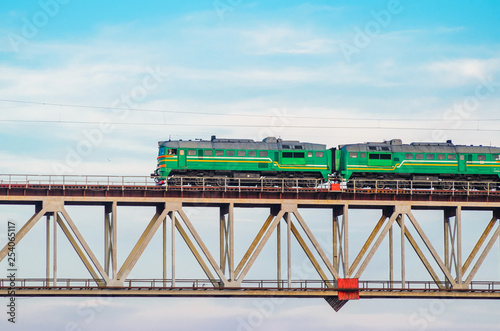 Green Cargo Locomotive Rides on a High Bridge Over the River