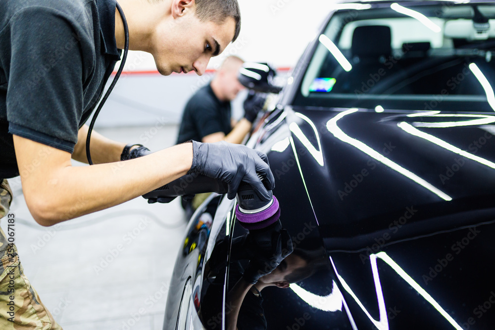 Car detailing - Worker with orbital polisher in auto repair shop. Car detailing - Worker with orbital polisher in auto repair shop.