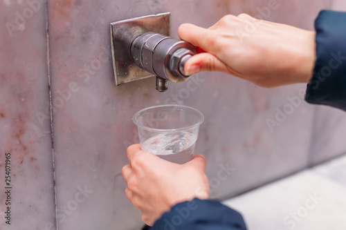 Yessentuki, Stavropol Territory / Russia - February 26, 2019: Drinking gallery of mineral spring Essentuki № 17. indoors. close - up of young woman gaining glass of mineral water from tap photo